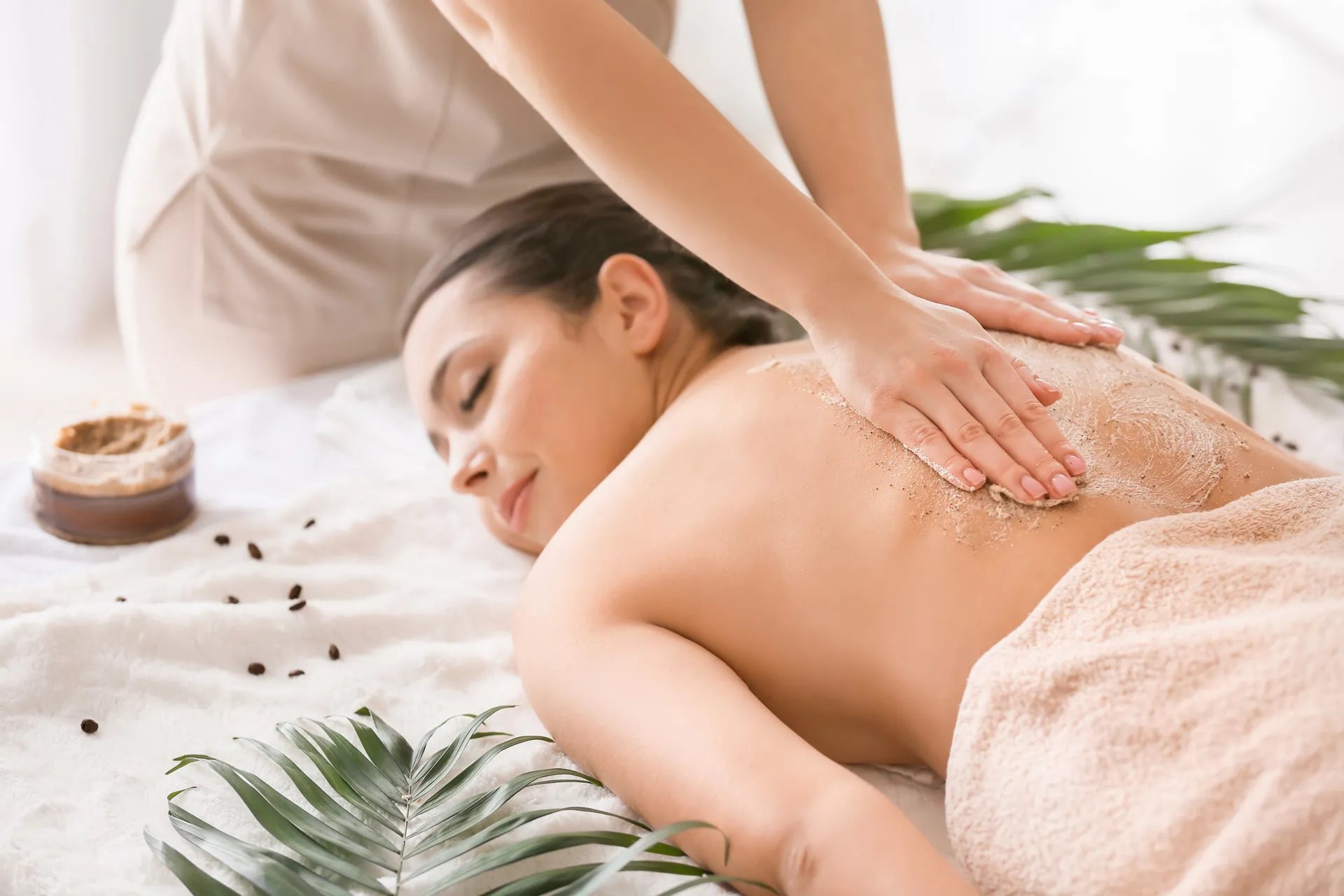 Gommage du dos d’une cliente allongée sur une table de soins.