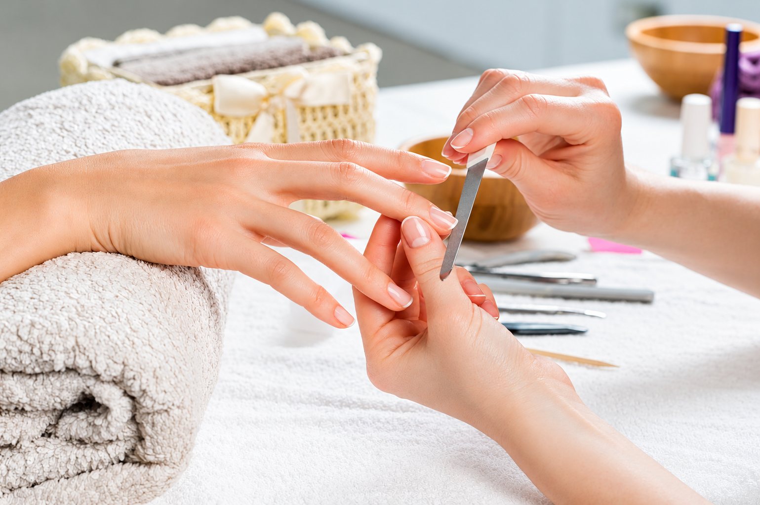 Limage des ongles d’une cliente, mains posées sur une serviette.